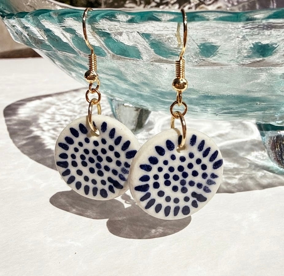 Pair of earrings with blue and white circular designs on a porcelian background