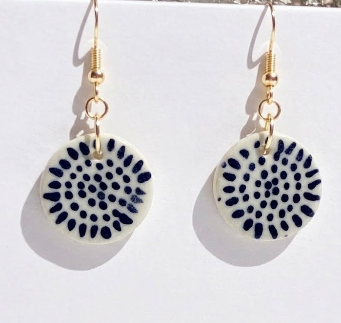 Pair of earrings with circular designs on a white background
