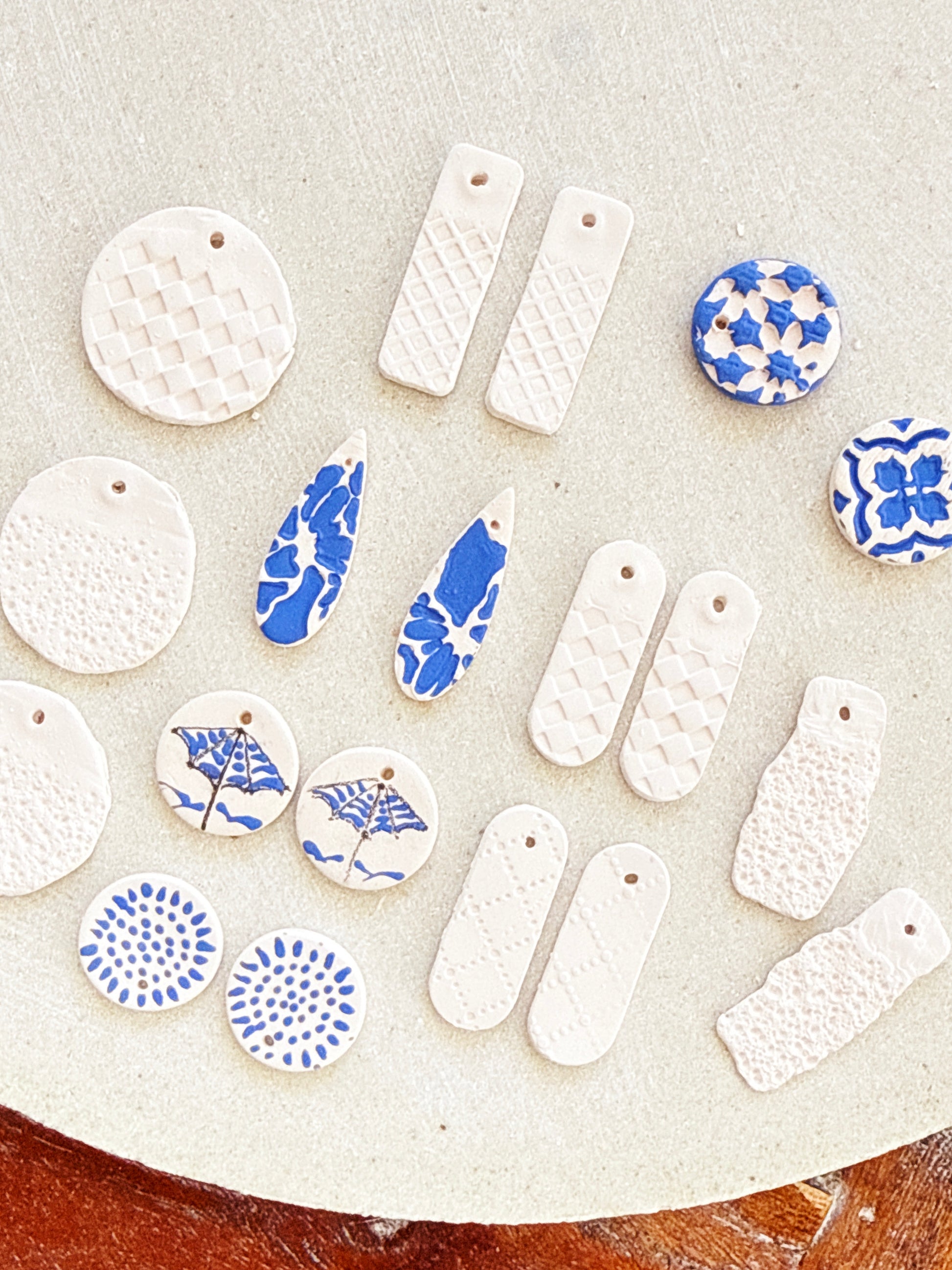 Collection of ceramic pendants with blue and white patterns on a textured surface